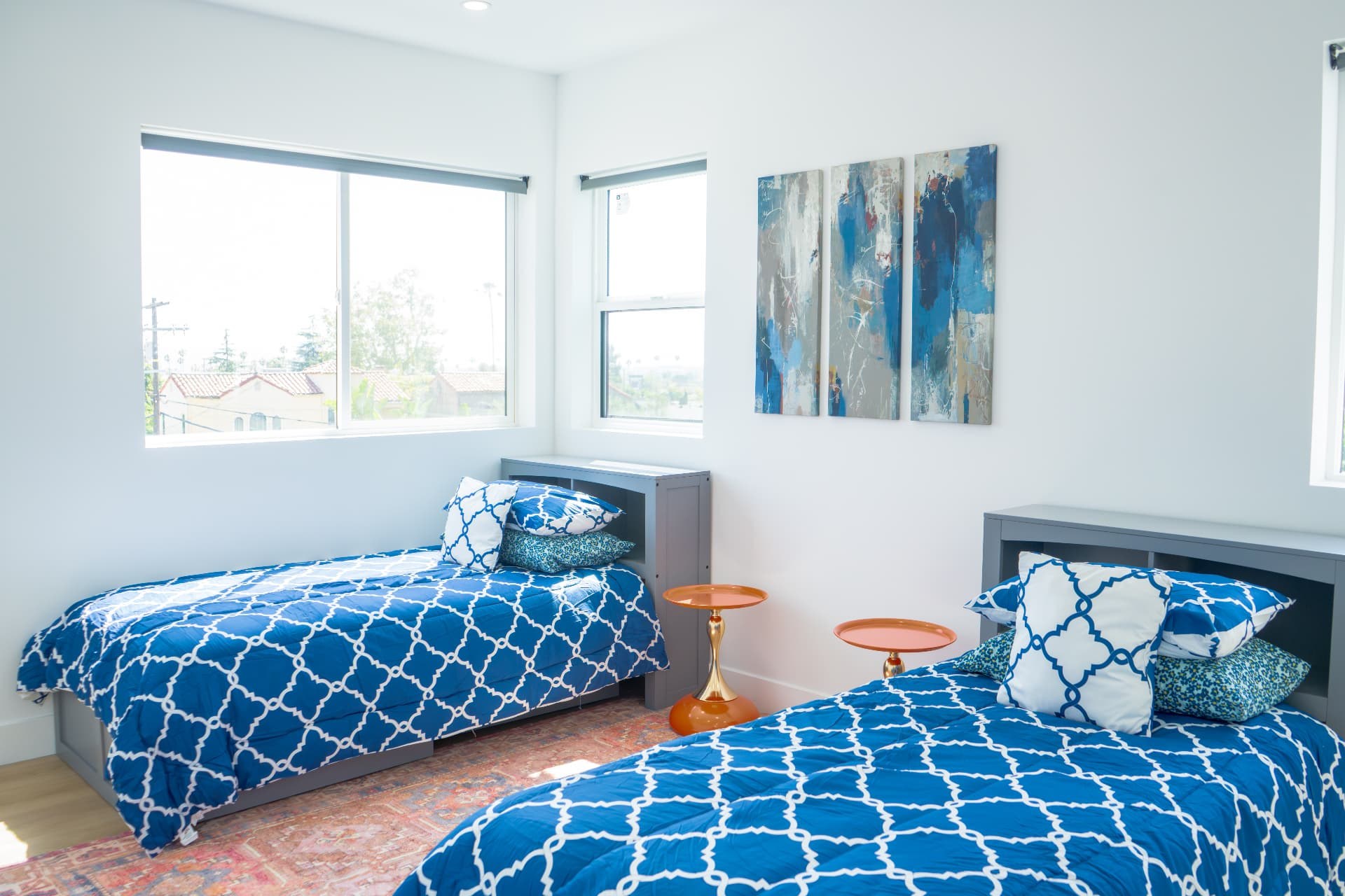 Shared bedroom with blue patterned bedding and three-panel artwork