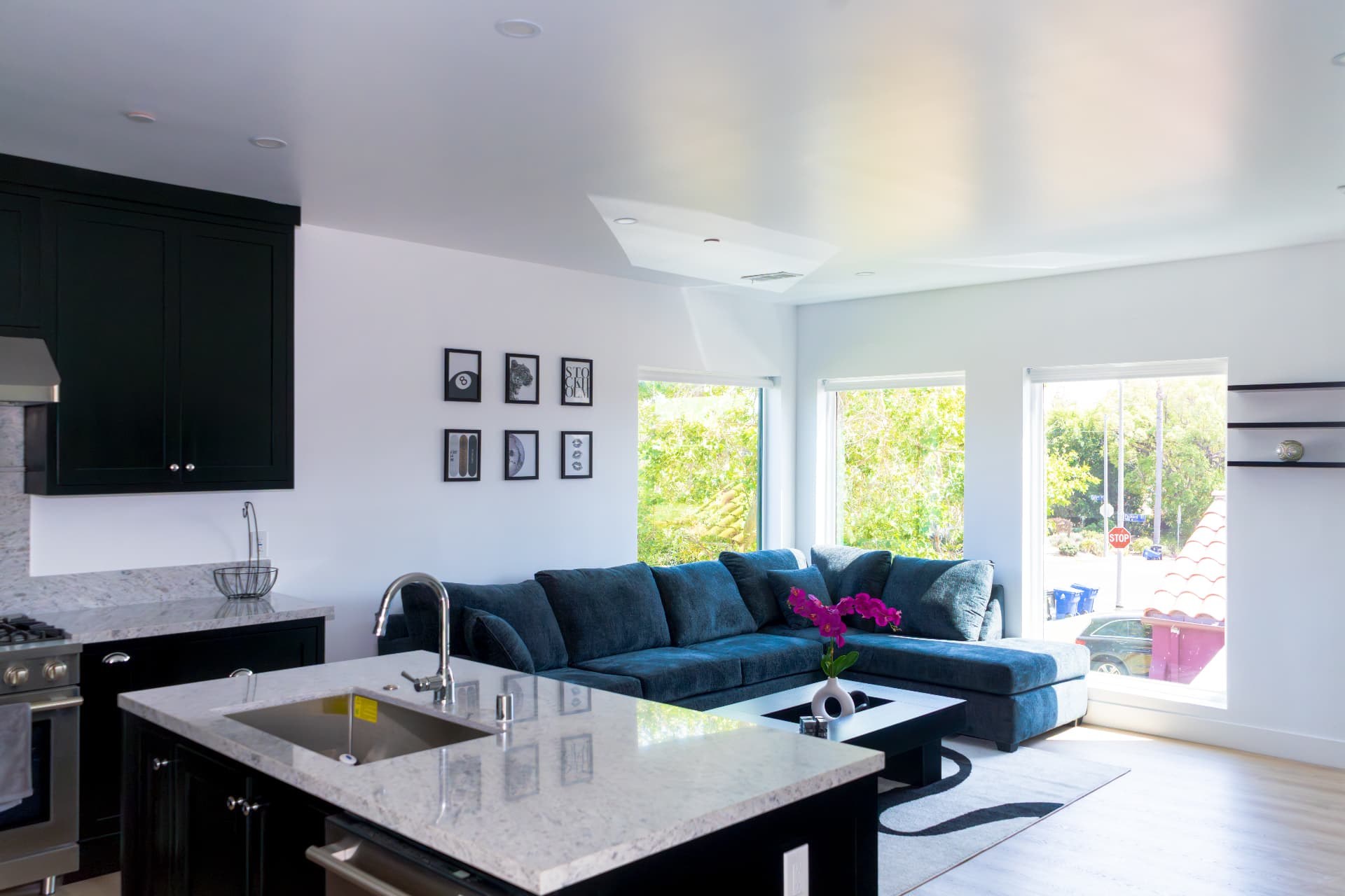 Open kitchen and living area with a marble island and navy sectional sofa